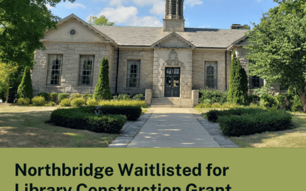 Stone library building with symmetrical entrance, manicured bushes, and trees in front; blue sky above. Text reads: 