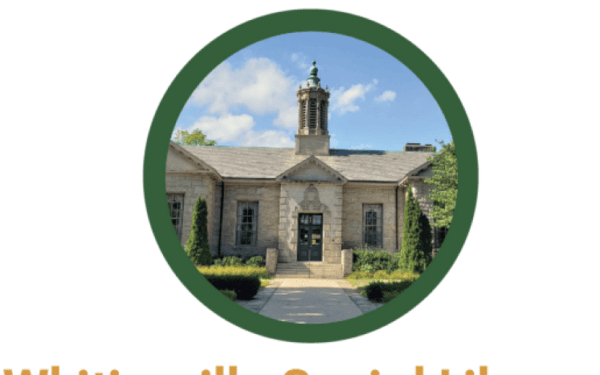 A small stone building with a central entrance and a cupola on the roof, viewed under a blue sky with some greenery around it.